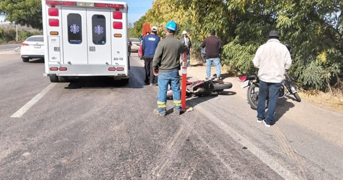 Accidente de motocicleta en carretera rural con ambulancia y personas asistiendo.