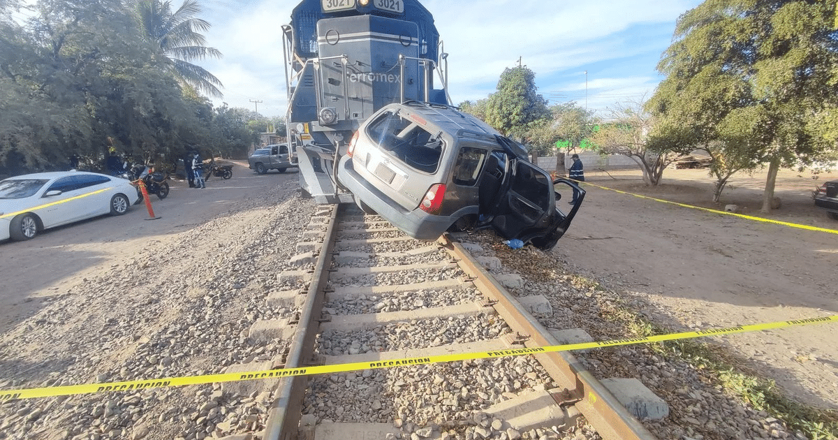 Automóvil volcado en vías del tren en Cuatro Milpas, con tren de carga cercano y cinta de precaución.