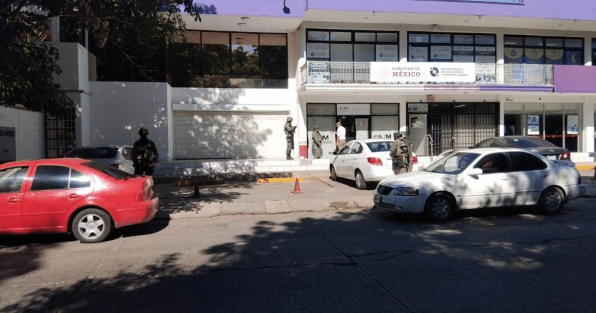 Calle con vehículos detenidos, personal militar y edificio del Gobierno de México en Culiacán.