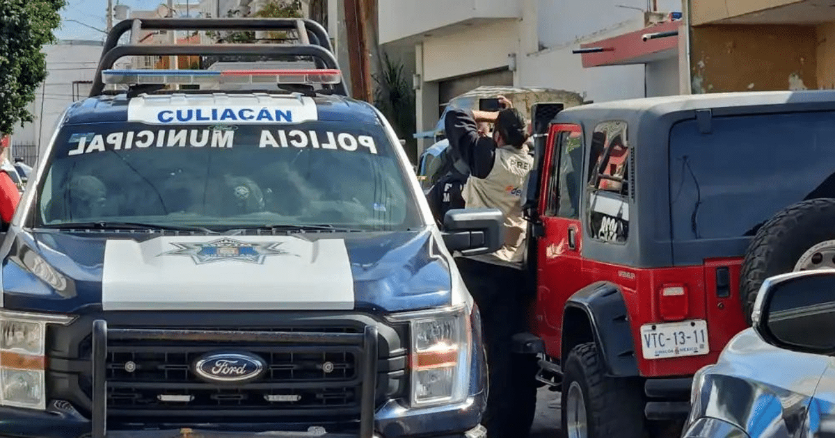 Vehículo de policía de Culiacán y hombre grabando junto a un todoterreno rojo en una escena urbana.