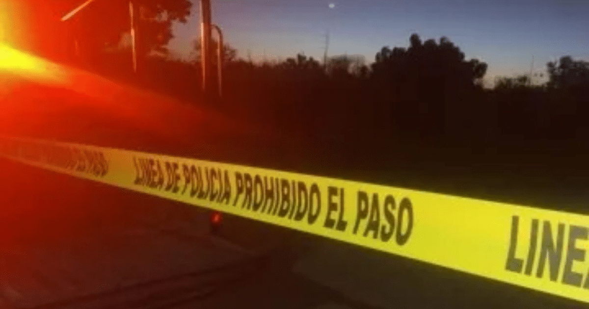 Cinta de policía amarilla con texto de restricción de acceso en escena de crimen nocturna.