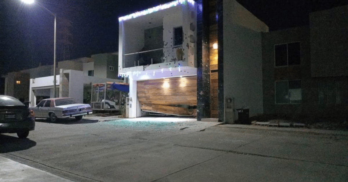 Calle de noche en Culiacán con casa dañada y vehículos estacionados