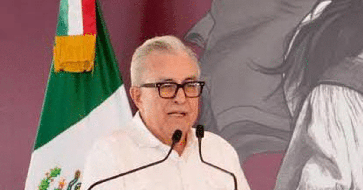 Gobernador Rubén Rocha Moya hablando en conferencia de prensa con bandera de México al fondo