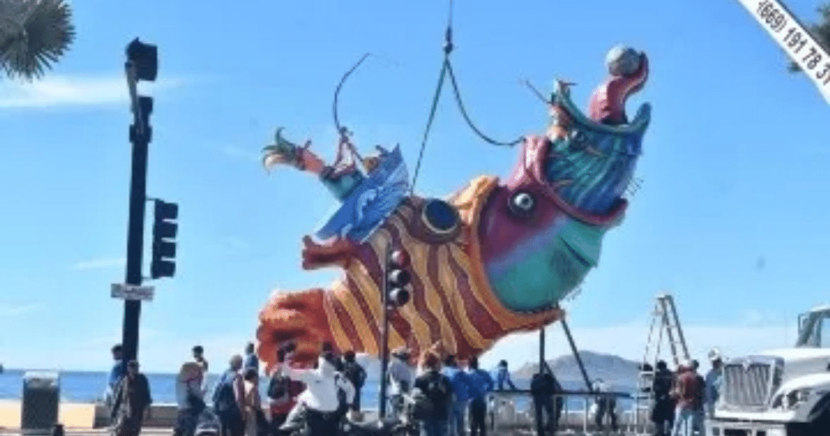 Estructura colorida levantada por grúas en un paisaje costero, relacionada con el Carnaval de Mazatlán.