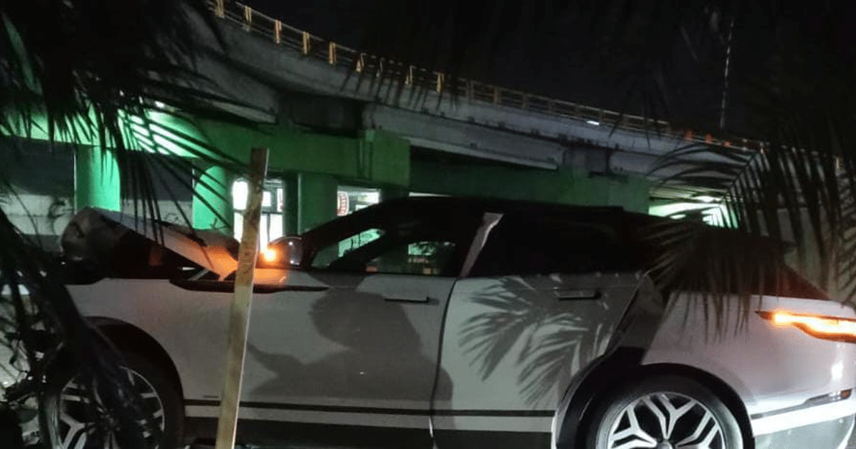 Vehículo blanco estacionado bajo luces de colores con puente al fondo, relacionado con accidente en carretera internacional.