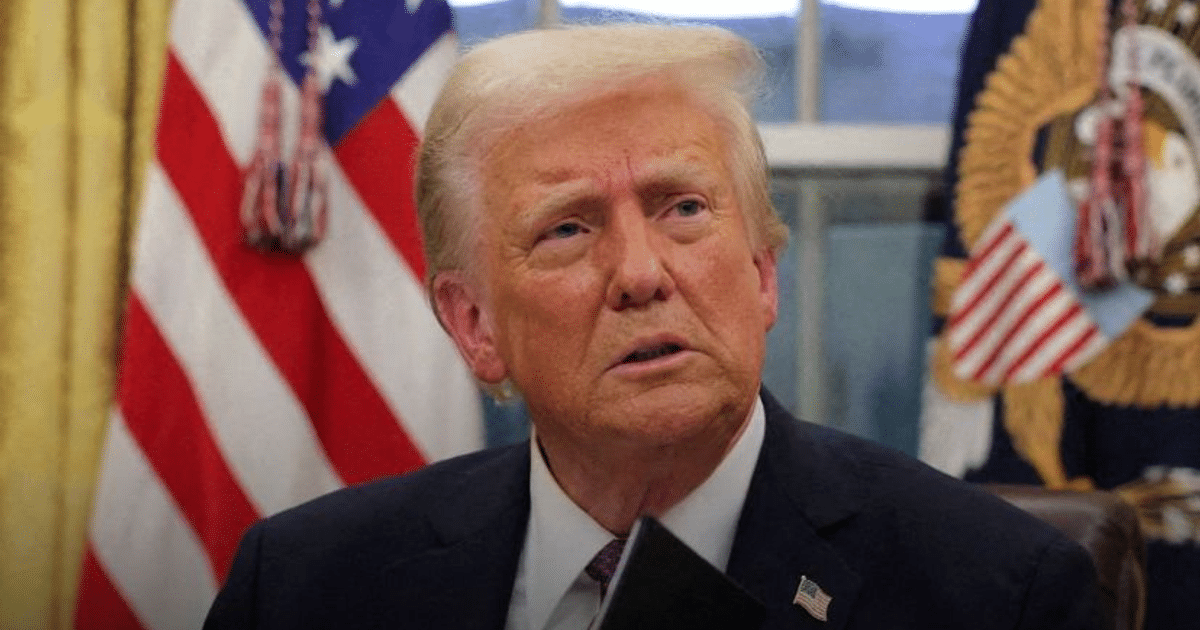 Persona en oficina con bandera, relacionada con demanda contra decreto de Trump sobre ciudadanía.