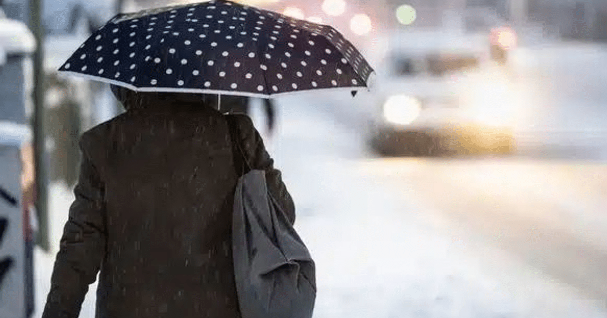 Persona con paraguas de puntos blancos en una ciudad nevada