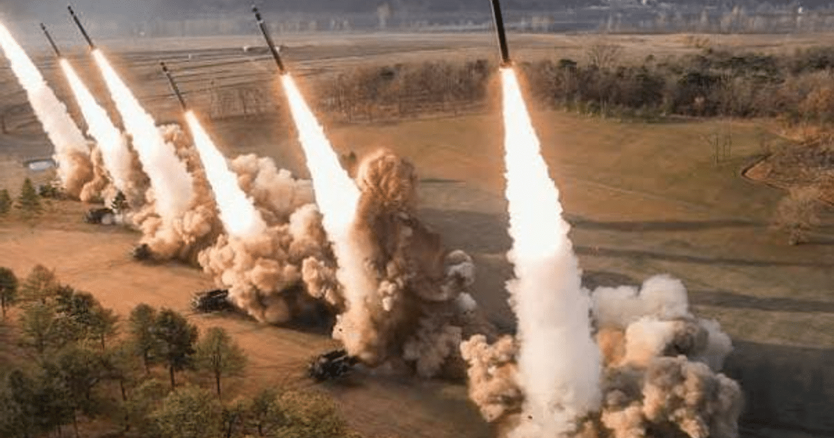 Lanzamiento de misiles en Corea del Norte durante una prueba militar, con humo y explosiones en un terreno despejado.