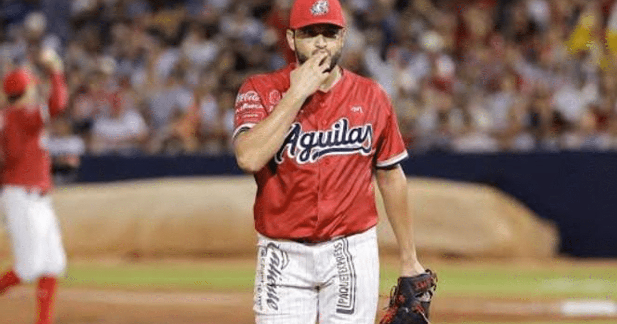 David Reyes en el campo de béisbol con uniforme de las Águilas, preparándose para lanzar.