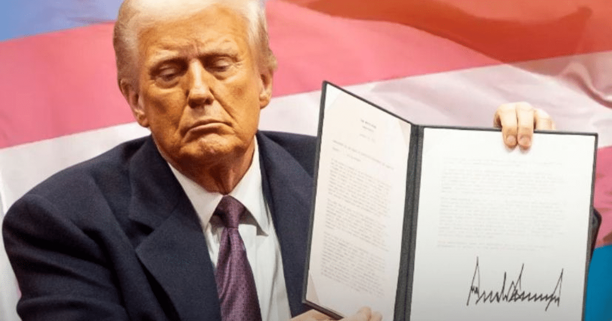 Persona sosteniendo un documento con fondo de colores, posiblemente una bandera, relacionada con decretos presidenciales sobre políticas transgénero.