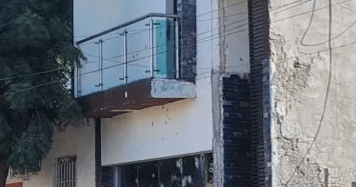 Fachada de edificio con balcón de vidrio y pared deteriorada en Prados del Sur, Culiacán, tras tiroteo.