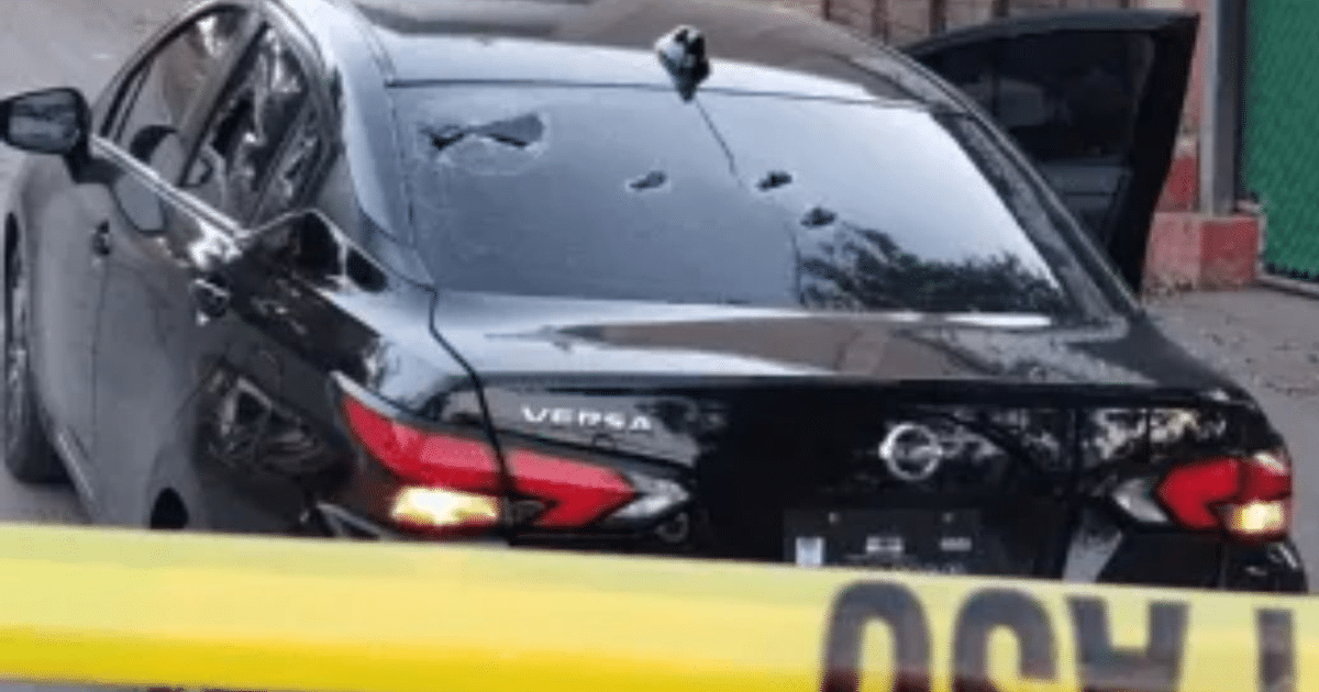 Automóvil Nissan Versa negro con impactos de bala y cinta de precaución en Culiacán.
