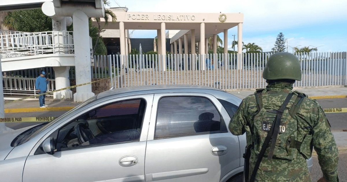 Soldado vigilando frente al Congreso de Culiacán con vehículo plateado y cinta de restricción.