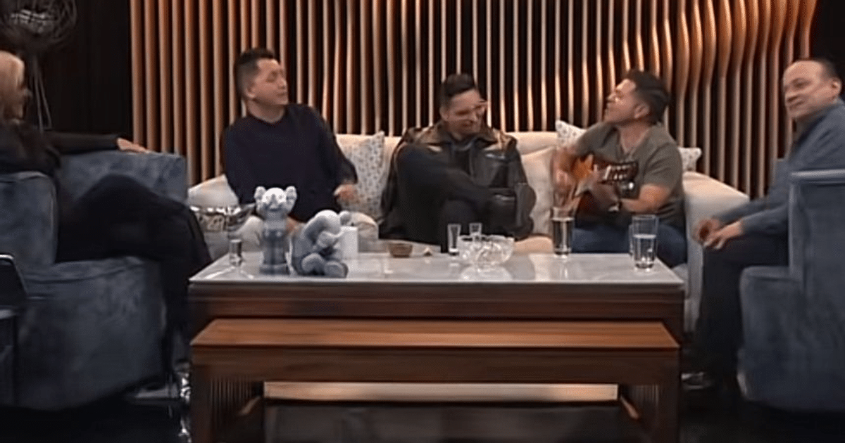 Grupo de personas en entrevista, hombre tocando guitarra, ambiente casual y moderno.