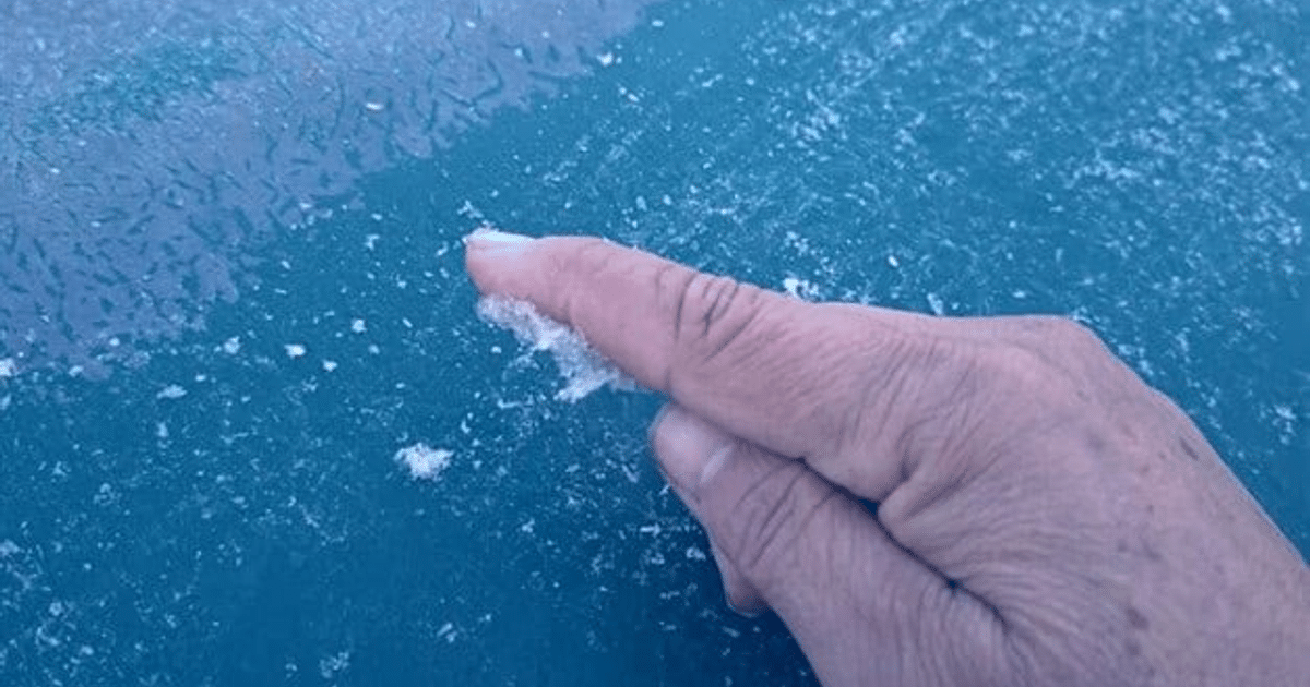 Mano tocando escarcha sobre fondo azul en Sinaloa