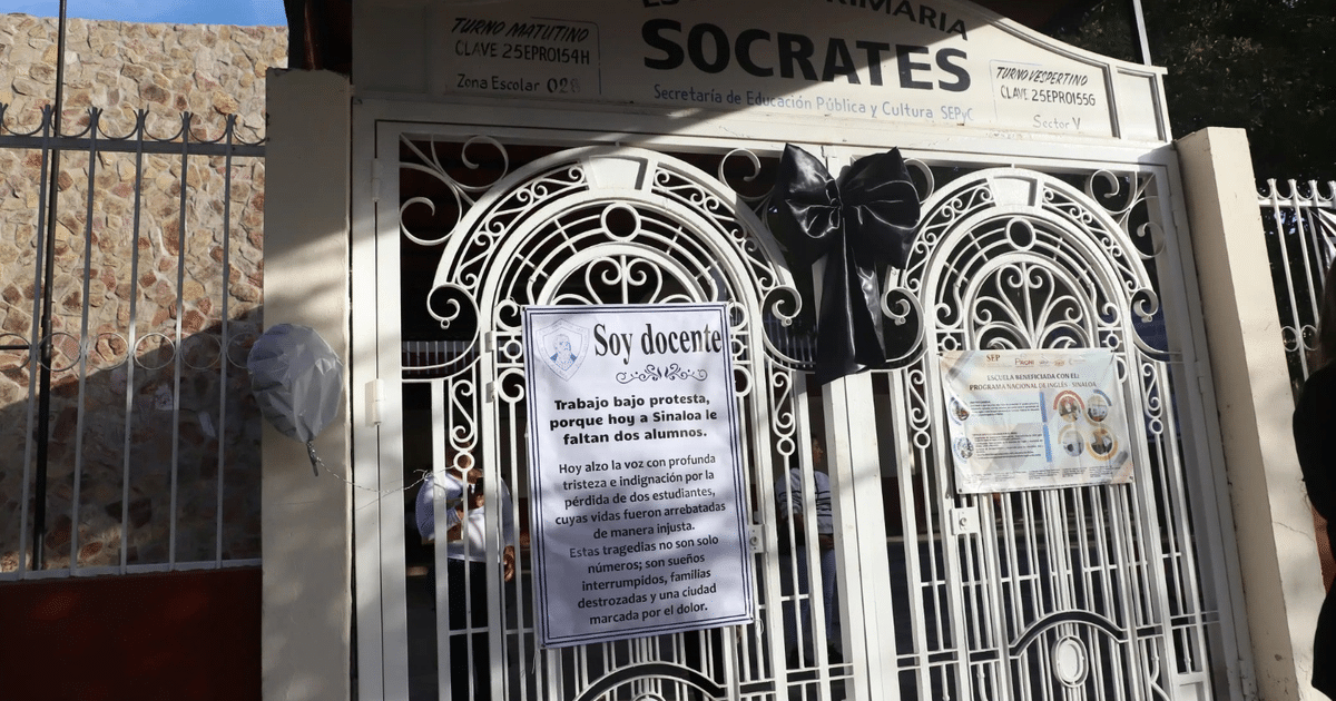 Entrada de la escuela Sócrates con moño negro y letrero de protesta por falta de alumnos.