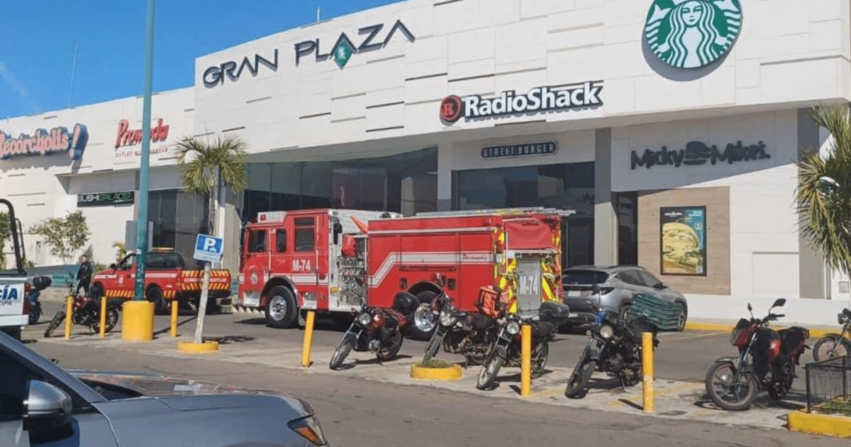 Camioneta de bomberos en la Gran Plaza de Mazatlán, con tiendas y vehículos alrededor en un día soleado.