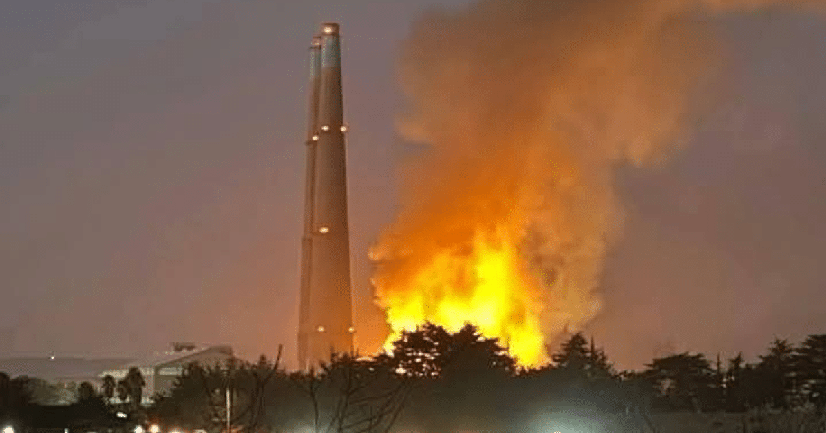 Chimenea industrial emitiendo humo y llamas durante la noche en la planta de energía de Moss Landing.