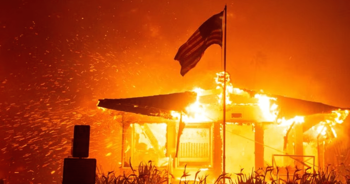 Edificio en llamas con bandera ondeando durante incendios forestales en California
