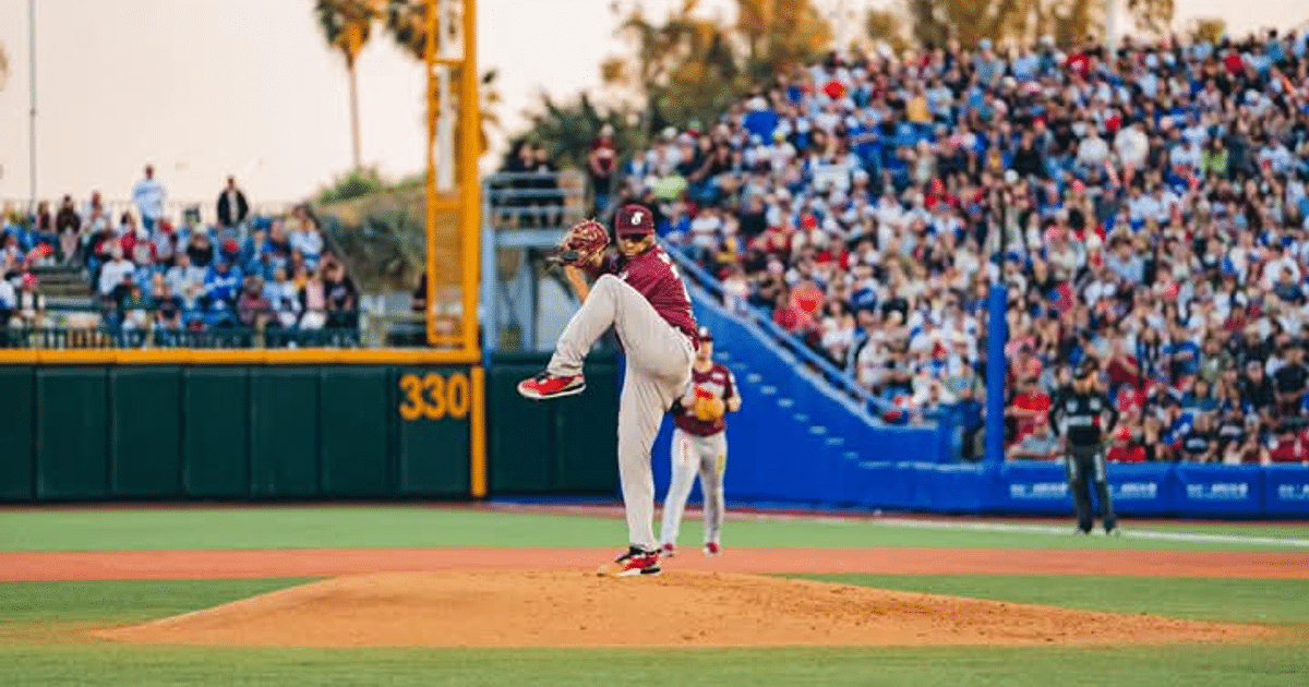 Lanzador de béisbol en el montículo durante un juego con espectadores en las gradas.
