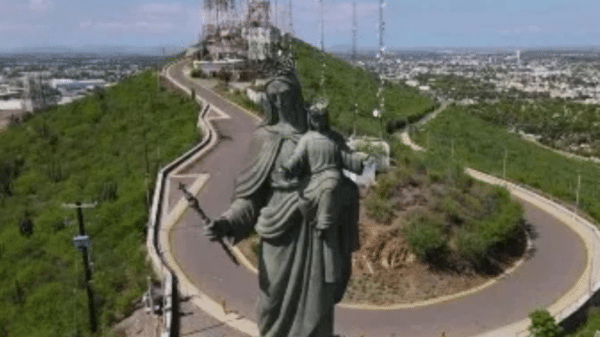 Estatua de la Virgen María con el Niño Jesús en una colina montañosa