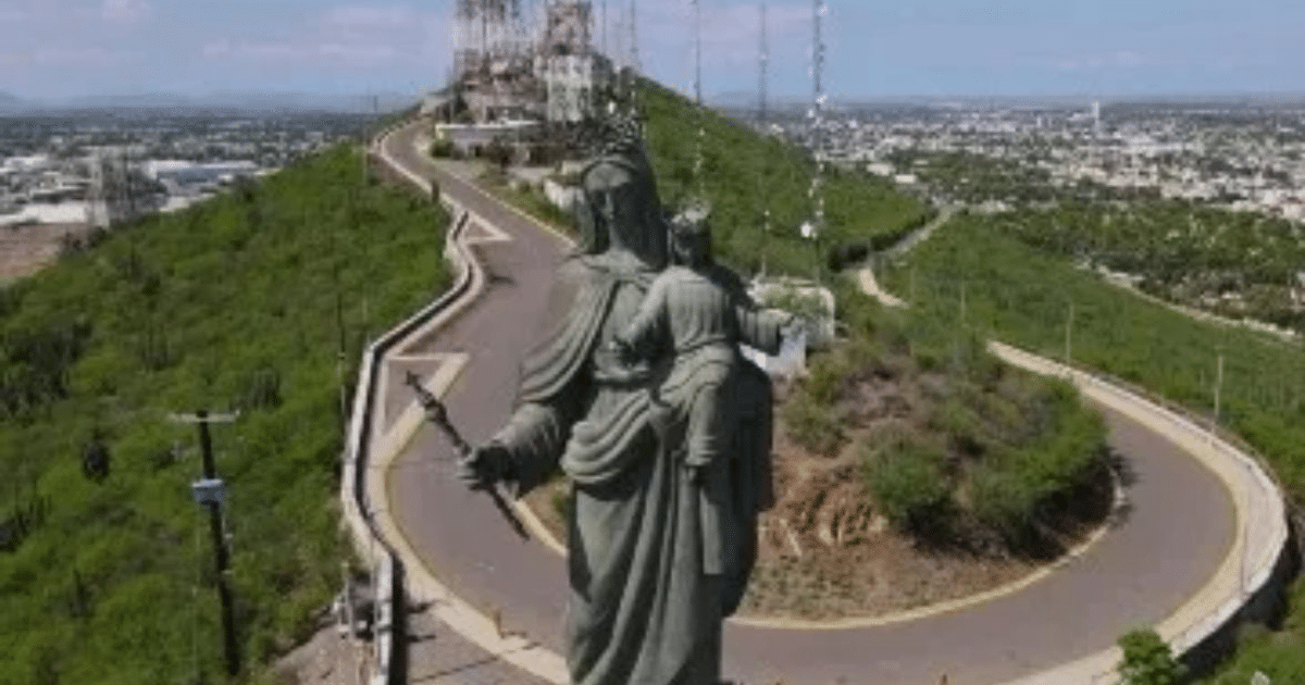 Estatua de la Virgen María con el Niño Jesús en una colina montañosa