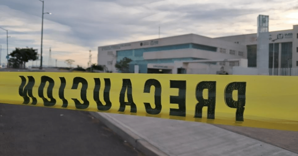Cinta de precaución amarilla frente a un edificio moderno al atardecer, sin personas visibles.