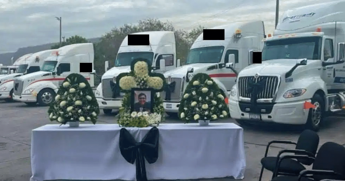 Altar con flores y fotografía de Luis Enrique en homenaje póstumo, rodeado de camiones de transporte.