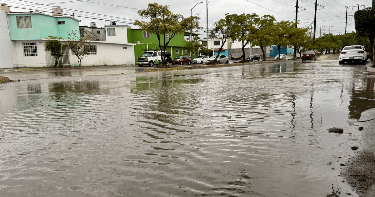 Calle inundada en Mazatlán con edificios de colores y cielo nublado