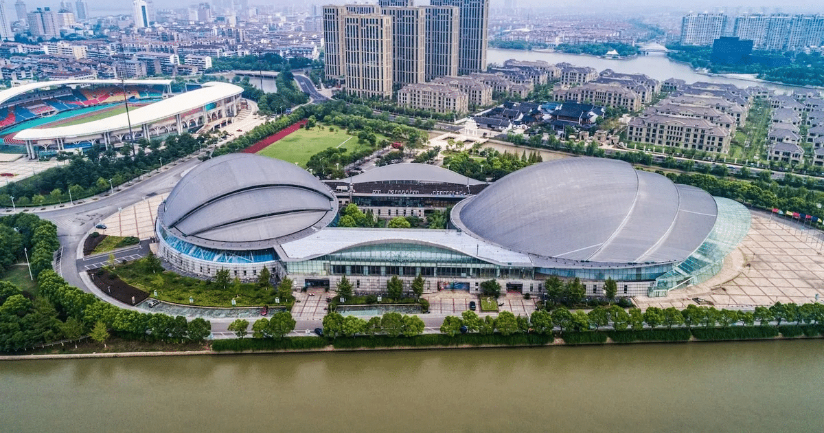 Vista aérea de un complejo deportivo moderno en Shanghái con un estadio y techos en forma de cúpula.