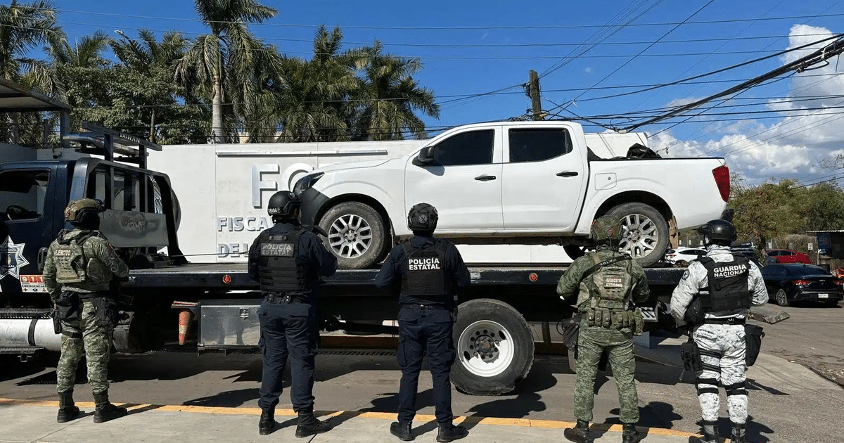 Agentes de seguridad inspeccionan una camioneta blanca sobre un camión de remolque en Culiacán, Sinaloa.