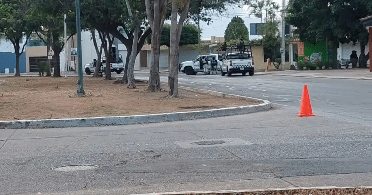 Calle bloqueada en Culiacán con cono de tráfico y vehículos de seguridad durante operativo militar.
