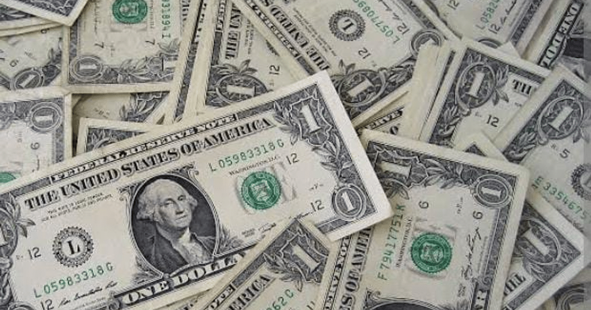 Billetes de un dólar estadounidense apilados y dispersos, representando la depreciación del peso mexicano.