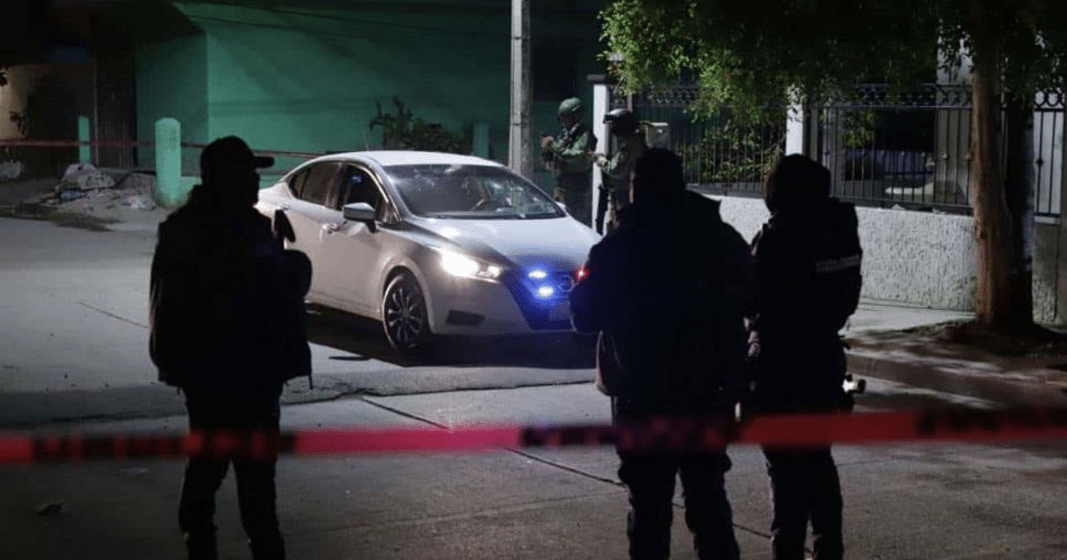 Escena nocturna con operativo policial en Mazatlán, vehículo blanco y cinta de advertencia.