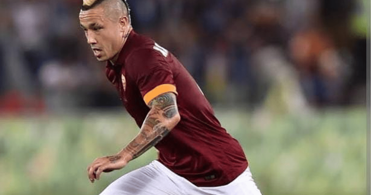 Jugador de fútbol con camiseta burdeos y pantalones blancos corriendo en el campo