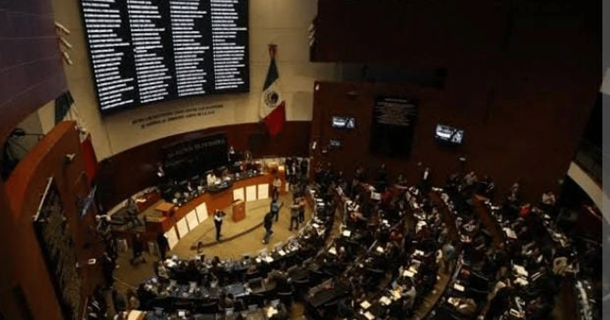 Interior del Senado de México con personas en sesión parlamentaria y pantalla de resultados al fondo.
