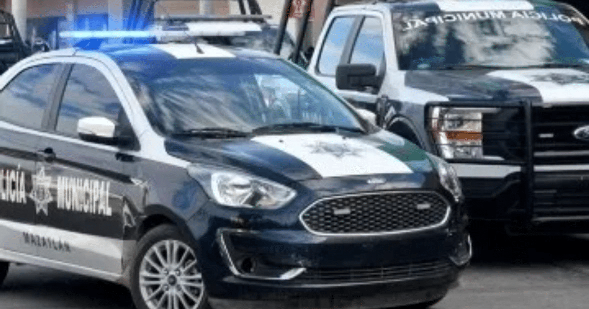 Dos vehículos de la Policía Municipal de Mazatlán, un auto y una camioneta, en colores blanco y negro con luces de emergencia.