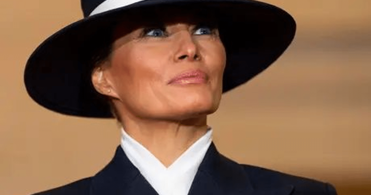 Retrato oficial de Melania Trump en blanco y negro, de pie junto a una mesa en el Despacho Oval, con el Obelisco de Washington al fondo.