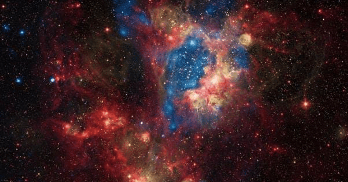 Imagen de una nebulosa con estrellas brillantes y nubes de gas en tonos rojo, azul y amarillo.