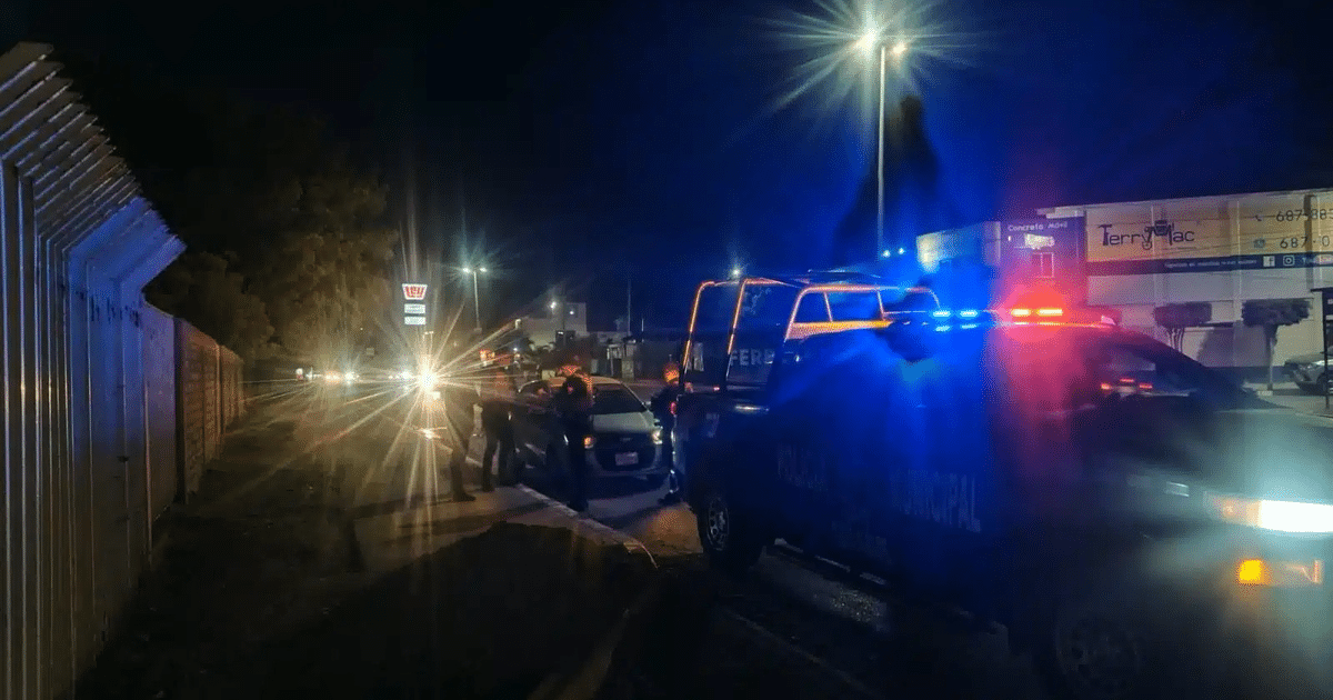 Operativo policial nocturno en Guasave con luces de emergencia y policías alrededor de un automóvil detenido.