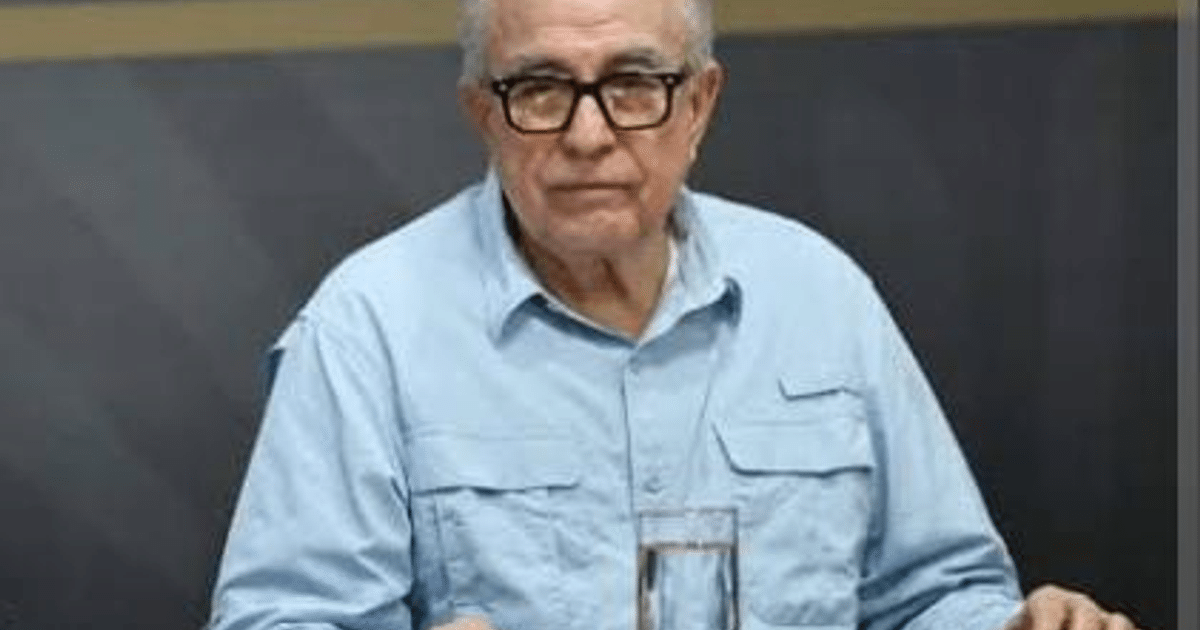 Hombre mayor con gafas y camisa azul sentado a una mesa con un vaso de agua, relacionado con la libertad de expresión en Sinaloa.
