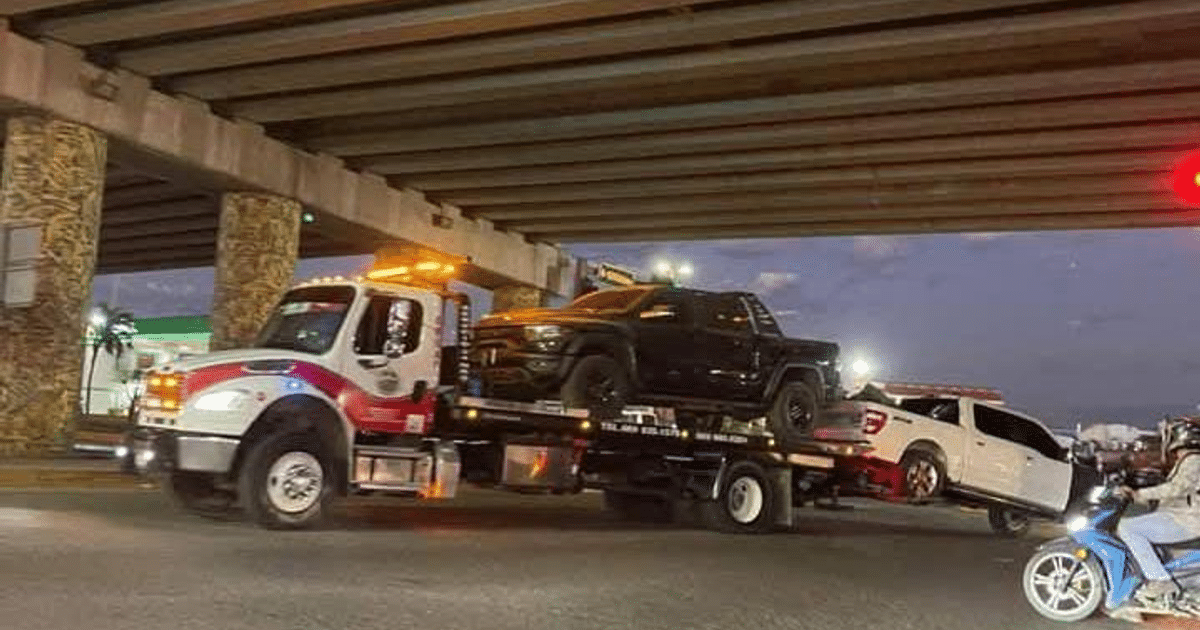 Camión de remolque con camioneta negra y vehículo blanco bajo un puente, parte de un operativo de la Marina en Mazatlán.