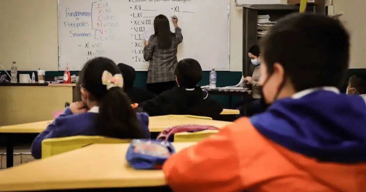 Estudiantes en un aula escolar en Culiacán, Sinaloa, con una docente escribiendo en la pizarra y algunos usando mascarillas.