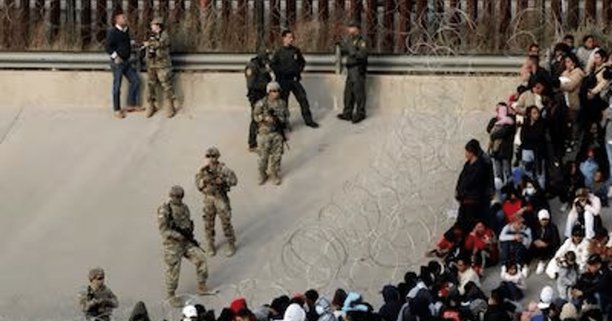 Soldados y agentes de seguridad en la frontera de Texas, con una valla de alambre de púas al fondo.