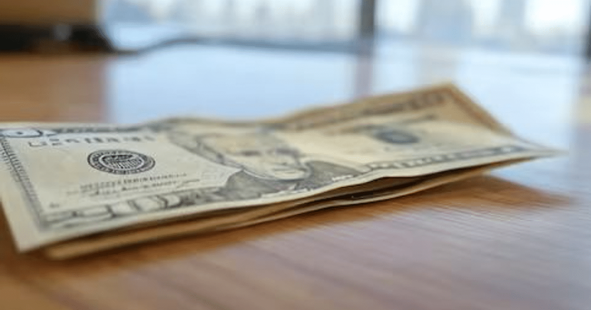 Billetes de dinero sobre una mesa de madera en una oficina iluminada naturalmente.
