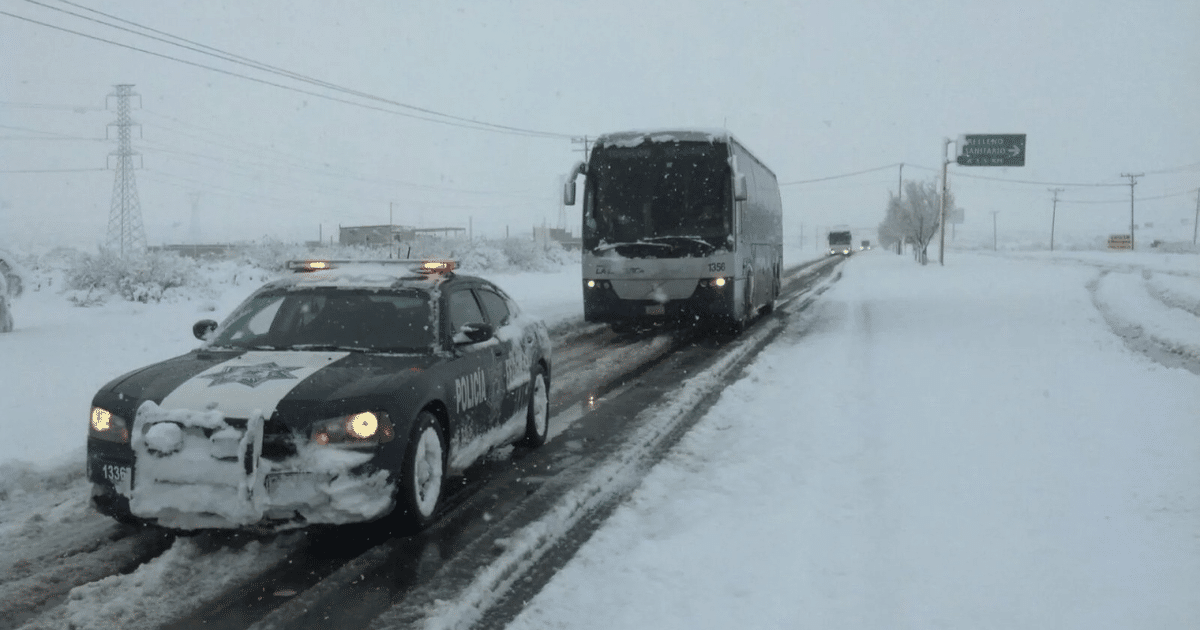 Patrulla de policía en carretera nevada con autobús al fondo durante tormenta invernal en Ahome.