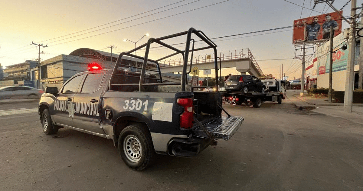 Camioneta de policía municipal número 3301 en operativo urbano al atardecer, con remolque y automóvil en el fondo.