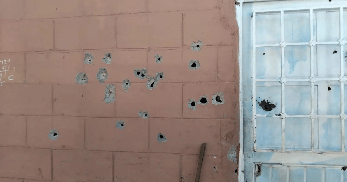 Pared rosa con agujeros de bala y puerta blanca en Culiacán
