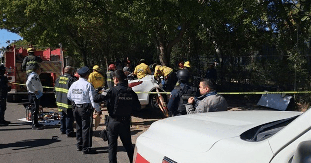 Personal de emergencia y policías en escena de accidente vial en Culiacán, con camión de bomberos y cintas de seguridad.