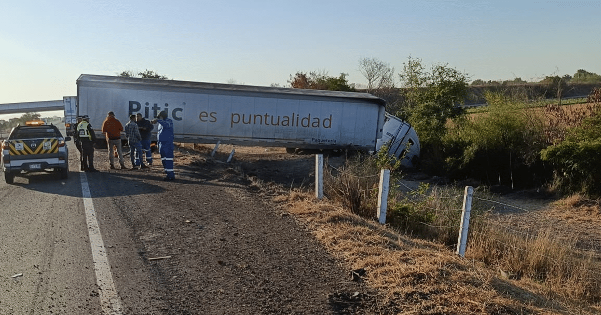 Camión de carga volcado en Guamúchil, Sinaloa, con patrulla de policía y personas alrededor.